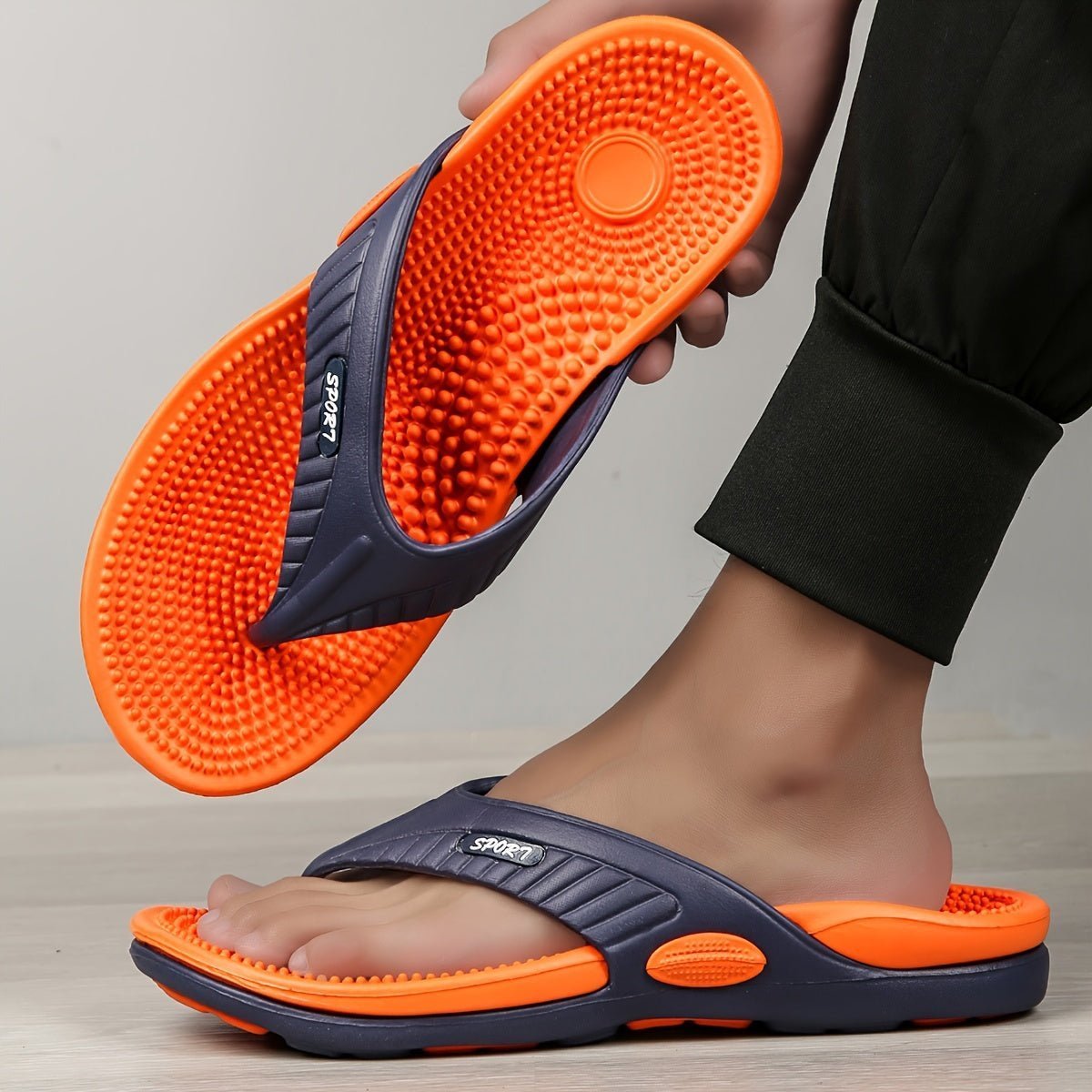 Men's EVA thongs in Orange, one held up to show the textured footbed