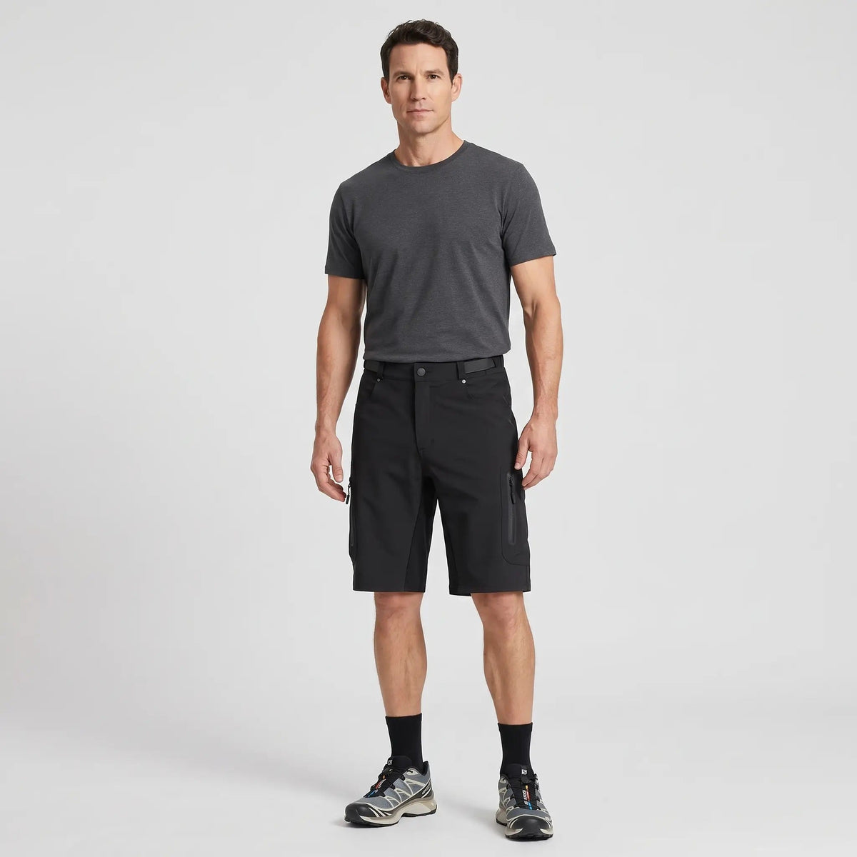 Man wearing the black MTB shorts with a charcoal T-shirt and trail shoes, full length