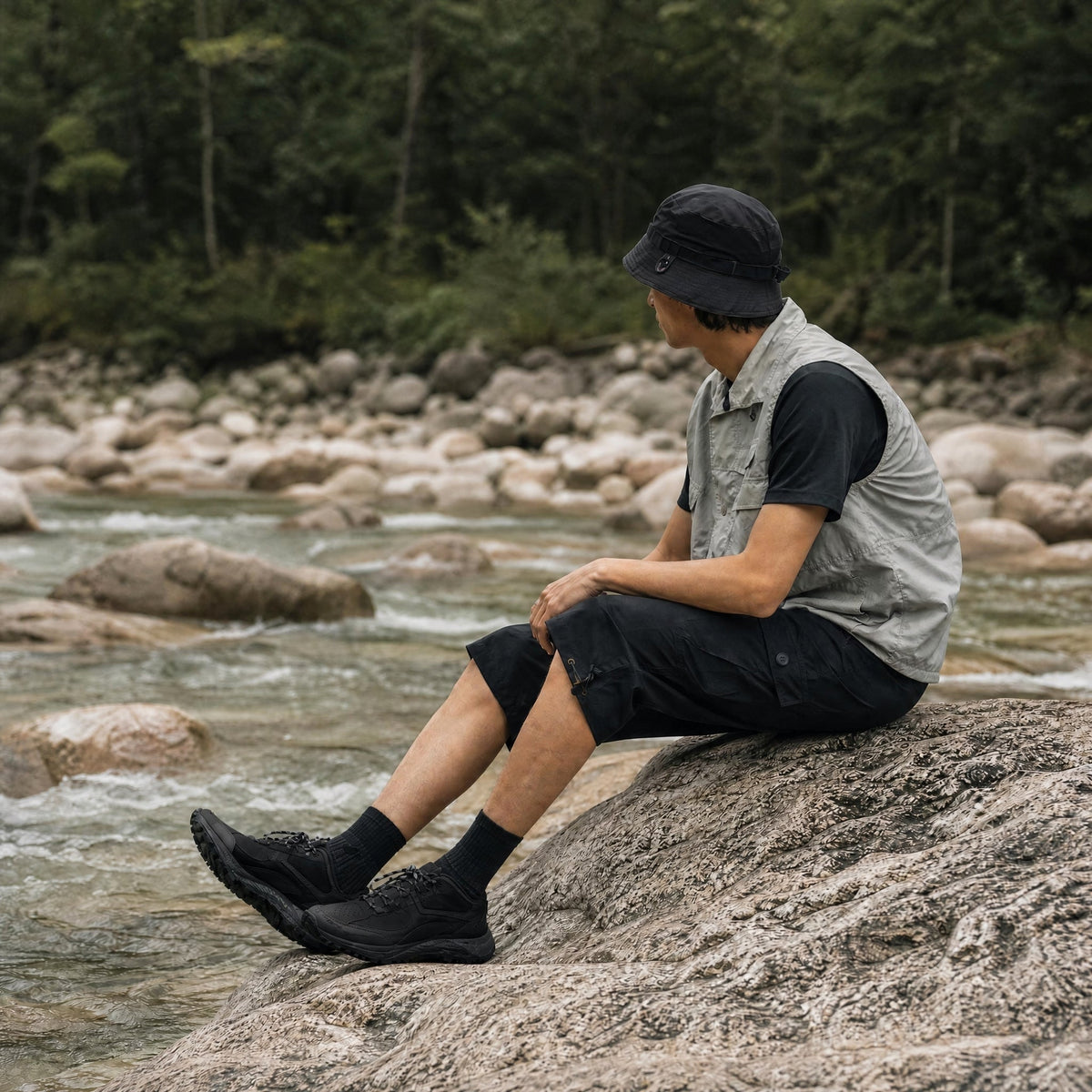 Man wearing the men's long cargo shorts in Black by a river